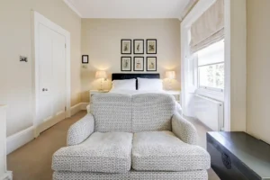 A cream coloured bedroom with a double bed and sofa.